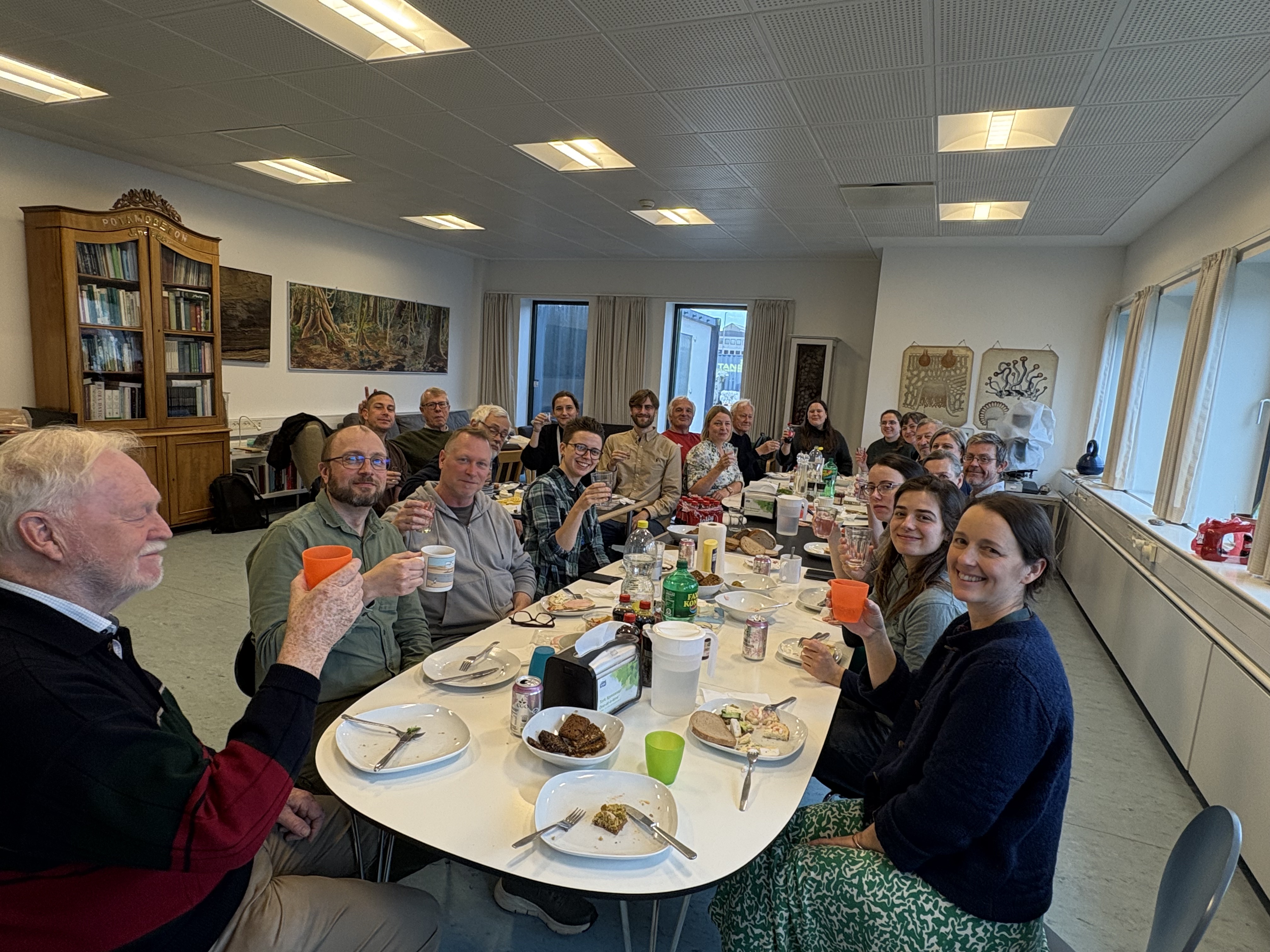 Many happy people at a long table, cheering